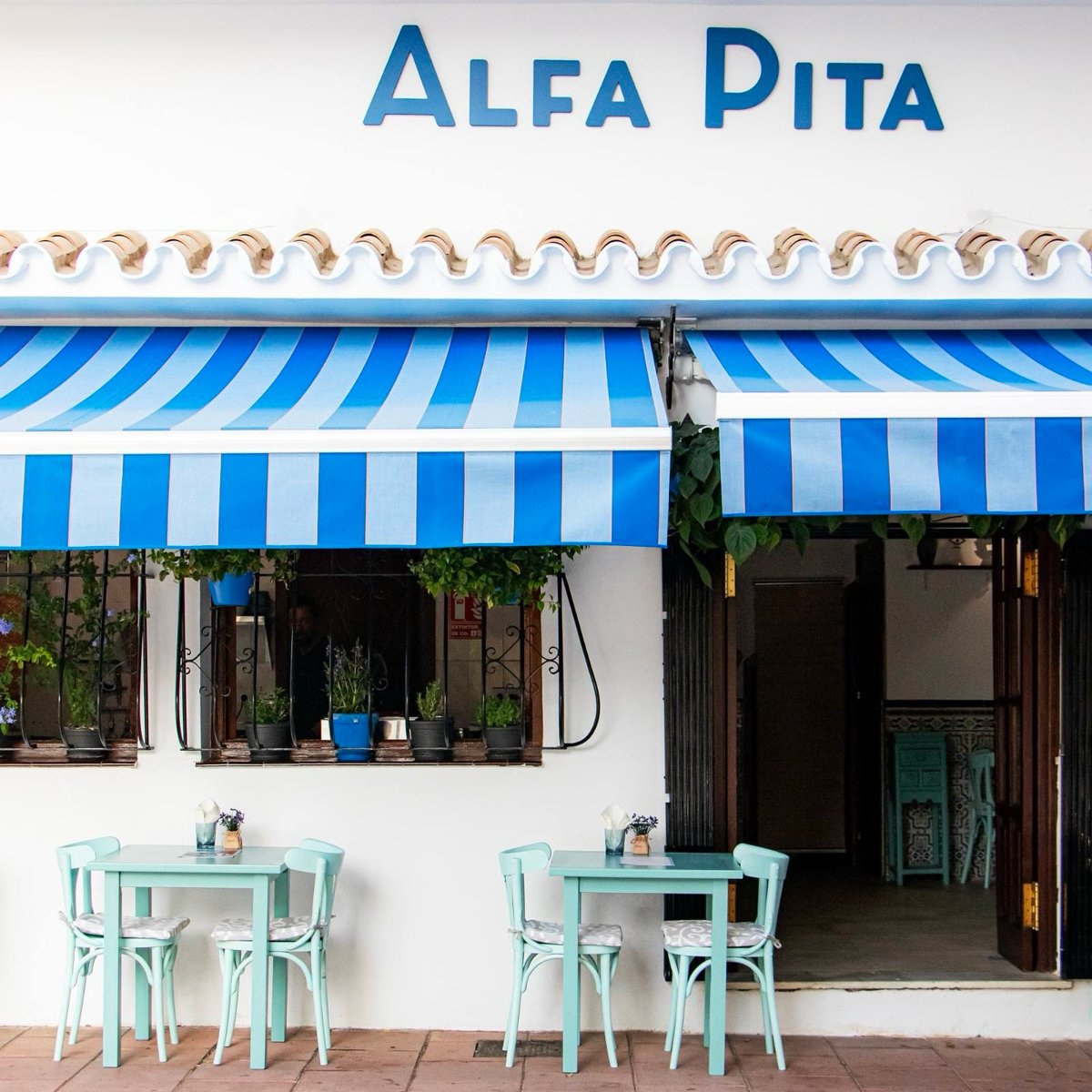 De blauw-witte gevel en het terras van Alfa Pita in Estepona