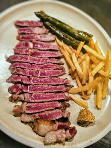 Een vleesgerecht met friet en groene asperges bij Oliva Iberoteca in Estepona